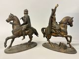pair of bronze statues of a man riding a horse and a woman riding a horse