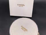 une montre Chanel dans un coffret blanc posé sur une surface noire