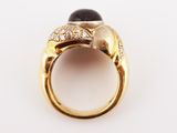 a close up of a gold ring with a black stone and diamonds