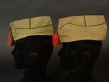 pair of black mannequin heads with hats and tassels on them