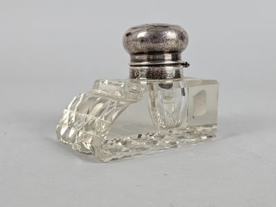 a small glass bottle with a silver top on a white surface