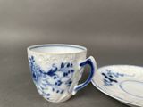 a blue and white cup and saucer sitting on a table