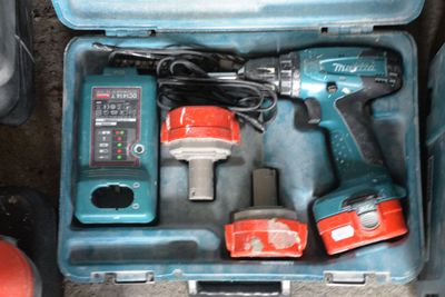 une mallette à outils bleue posée par terre, contenant des outils