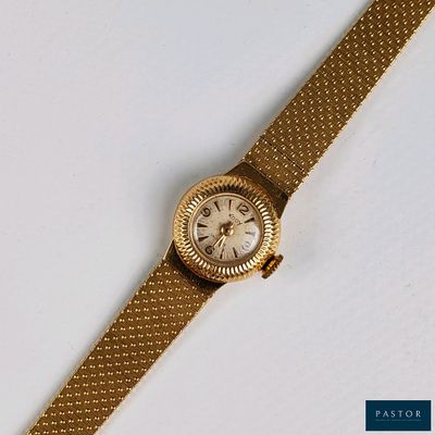 une image représentant une montre en or avec un cadran blanc posée sur une surface blanche