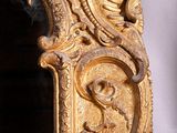 a mirror that has a gold frame with a picture on it