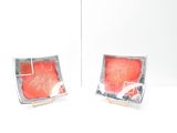 two square dishes with red and black designs on them