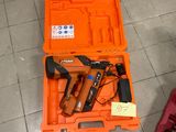 une boîte à outils contenant un marteau et une cloueuse, posée par terre