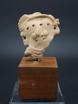 une petite statue représentant la tête d'un homme posée sur un bloc de bois