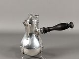 une cafetière en argent avec une poignée noire sur un fond gris