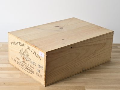 une caisse en bois sur laquelle est collée une étiquette, posée sur un plancher en bois