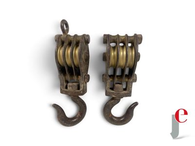 pair of antique cast iron pulleys with hooks on a white background