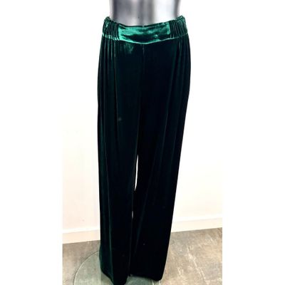 Le mannequin porte un pantalon en velours vert et un haut blanc.