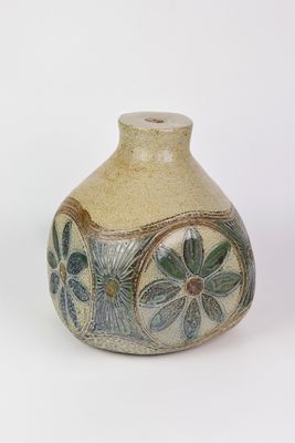 un petit vase posé sur une surface blanche