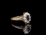 un gros plan d'une bague sertie d'un diamant et d'un saphir sur une surface noire
