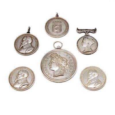 six silver coin pendants of various sizes and shapes on a white background