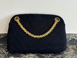 un sac à main noir matelassé muni d'une bandoulière en chaîne dorée