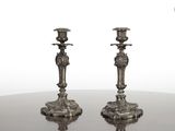 une paire de bougeoirs anciens en argent posés sur une table à miroir
