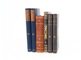 several old books are lined up on a shelf against a white background