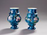 une paire de vases bleus ornés de fleurs, posés sur une surface blanche