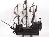 a wooden model of a pirate ship on a white surface
