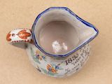 a small ceramic pitcher with a flower design on it