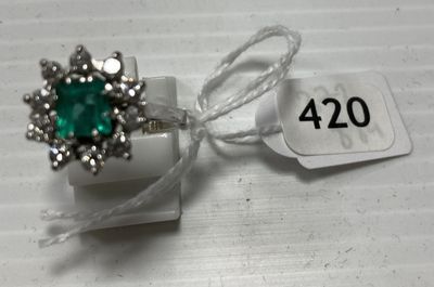 une bague sertie d'une pierre verte, posée sur une boîte blanche