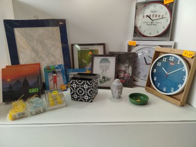 une étagère blanche sur laquelle se trouvent une horloge, des photos, des photos et d'autres objets