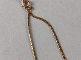 a close up of a gold plated necklace on a white surface
