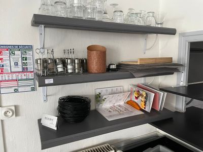 une petite cuisine équipée d'un micro-ondes et d'une étagère sur laquelle sont posés des verres