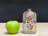 an apple next to a glass bottle on a table