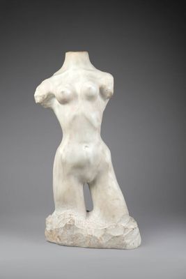 une sculpture blanche représentant un torse féminin posé sur un rocher