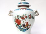 a white vase with a bird and flowers on it