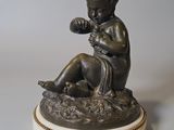statue d'un garçon assis sur un rocher, une fleur à la main