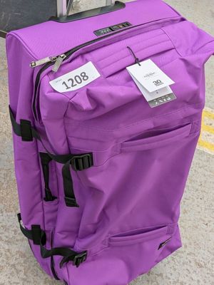 une valise violette avec une étiquette, posée par terre
