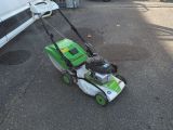 a green and white lawn mower sitting on the street