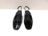 the black shoes are on a white surface with a white wall in the background