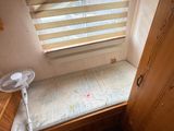 a small bed in the corner of a room with a fan