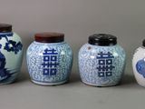 four blue and white vases are lined up against a gray background