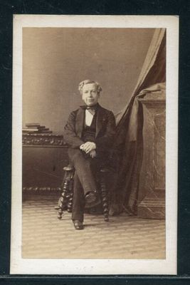 portrait d'un homme assis sur une chaise, sur une photo en noir et blanc