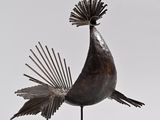 sculpture of a bird with feathers on its head on a white surface