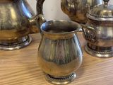 three silver teapots and two cups on a wooden table