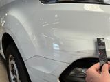 a person holding a remote control in front of a white car