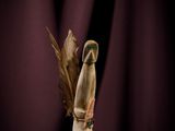 une petite figurine en bois ornée d'une plume, posée sur une table