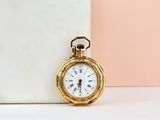 a small gold pocket watch sitting on a marble block