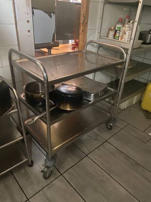 un chariot métallique sur lequel sont posés des casseroles et des poêles, dans une cuisine