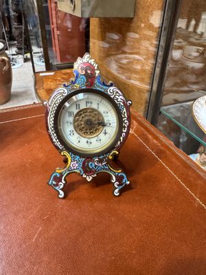 a small clock sitting on a table in front of a glass case