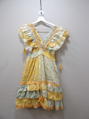yellow and green dress hanging on a hanger against a white wall