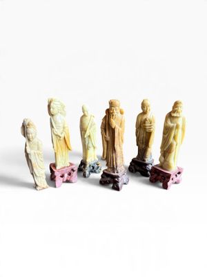 sept figurines de tailles et de formes différentes posées sur une surface blanche