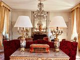 un salon avec une table, des canapés, des lampes et un lustre