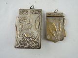 two pieces of silver jewelry that are on a table